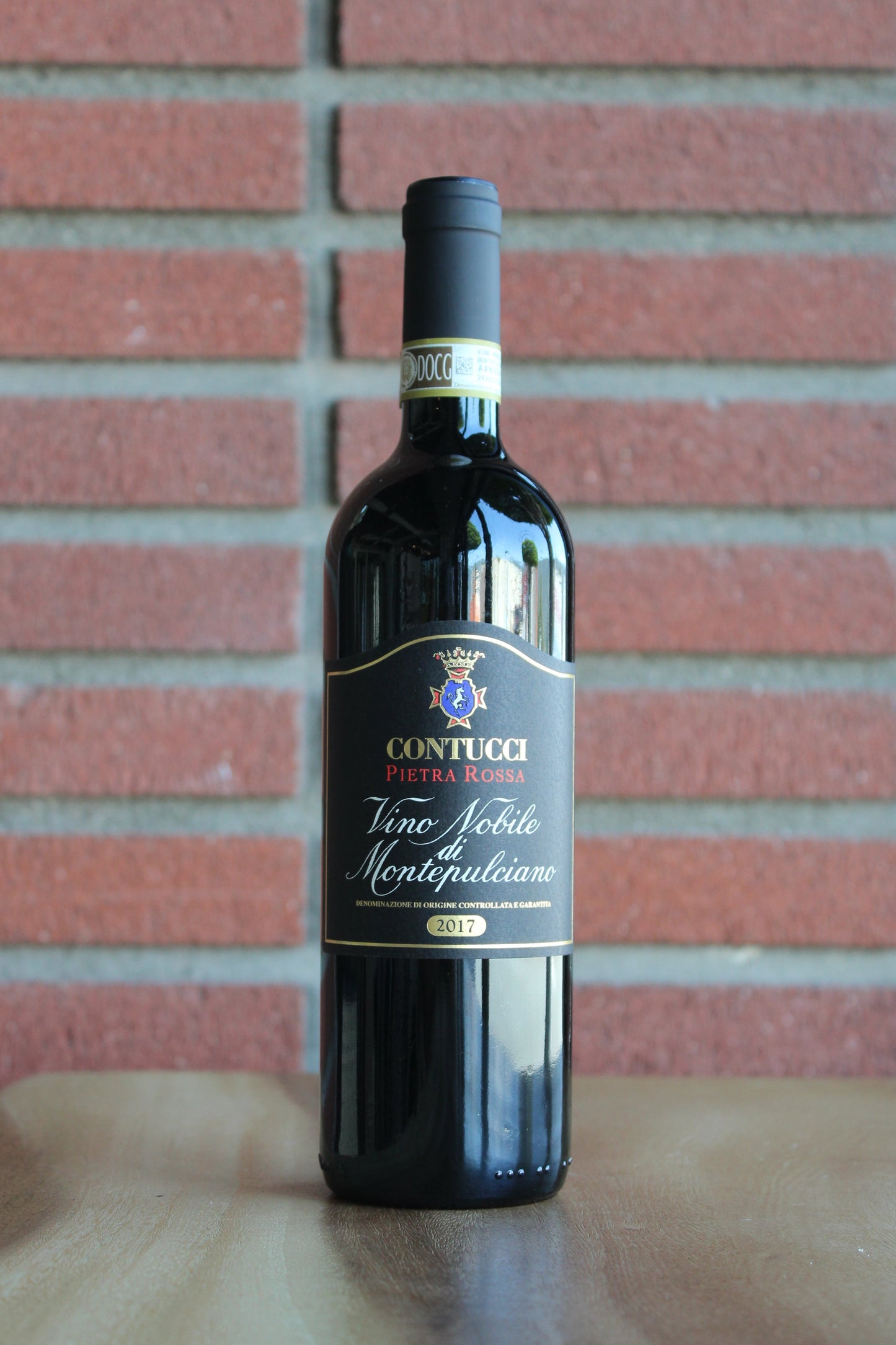 Bottle of Contucci Pietra Rossa Vino Nobile di Montepulciano on a brick background