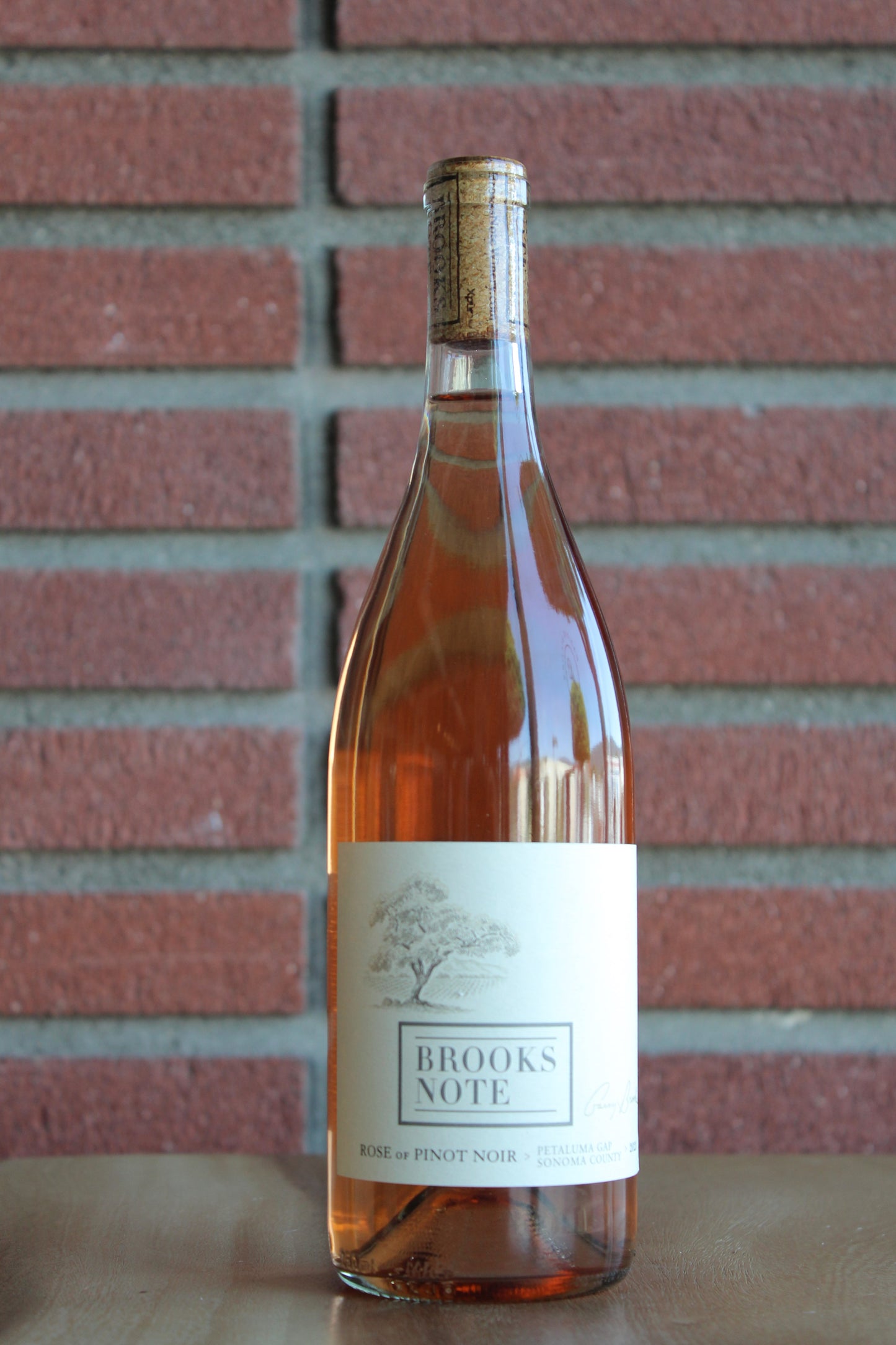 Bottle of Brooks Note Pinot Noir Rose against a brick background
