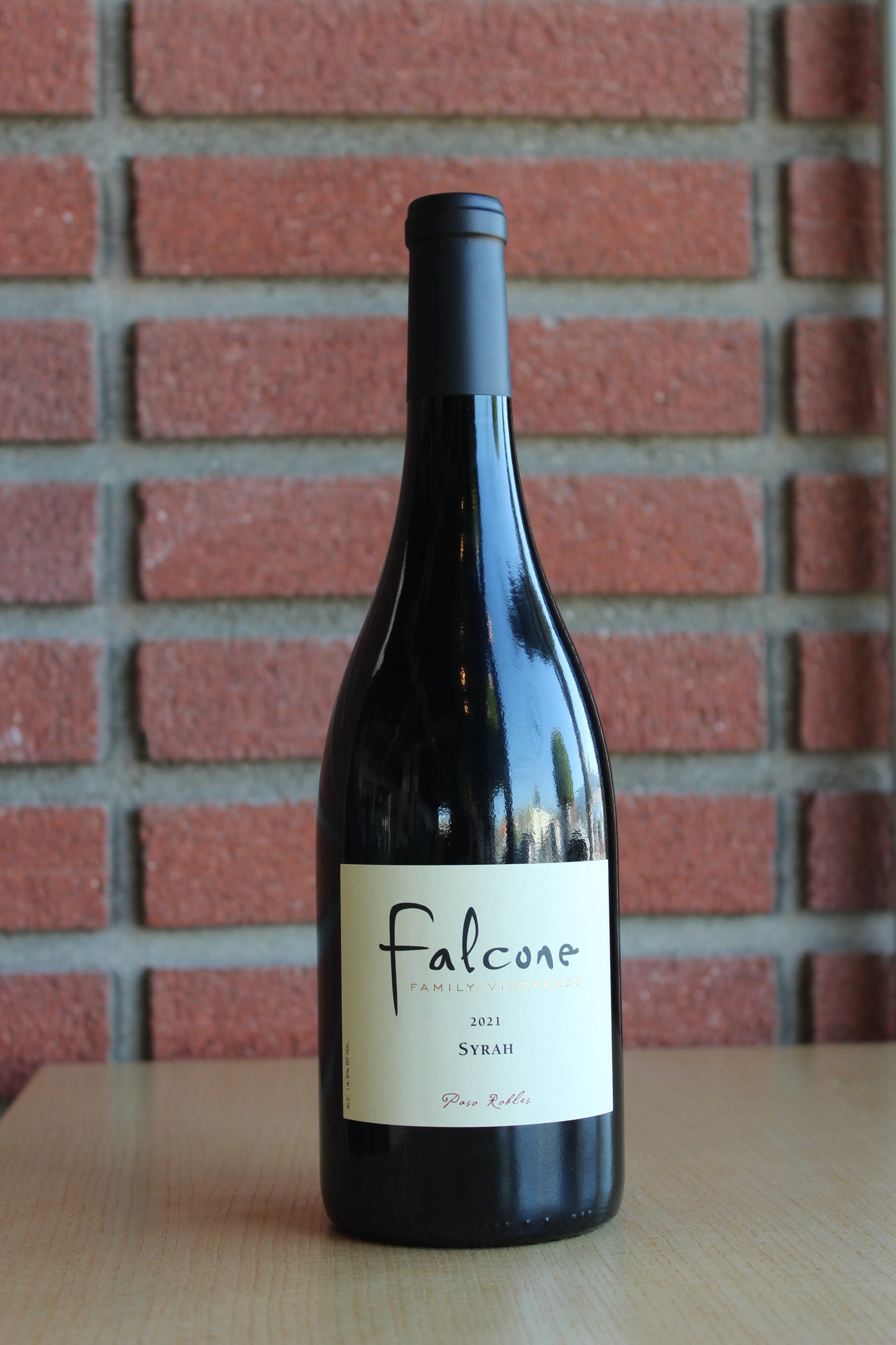 Falcone Family Vineyards Syrah Bottle on a brick background