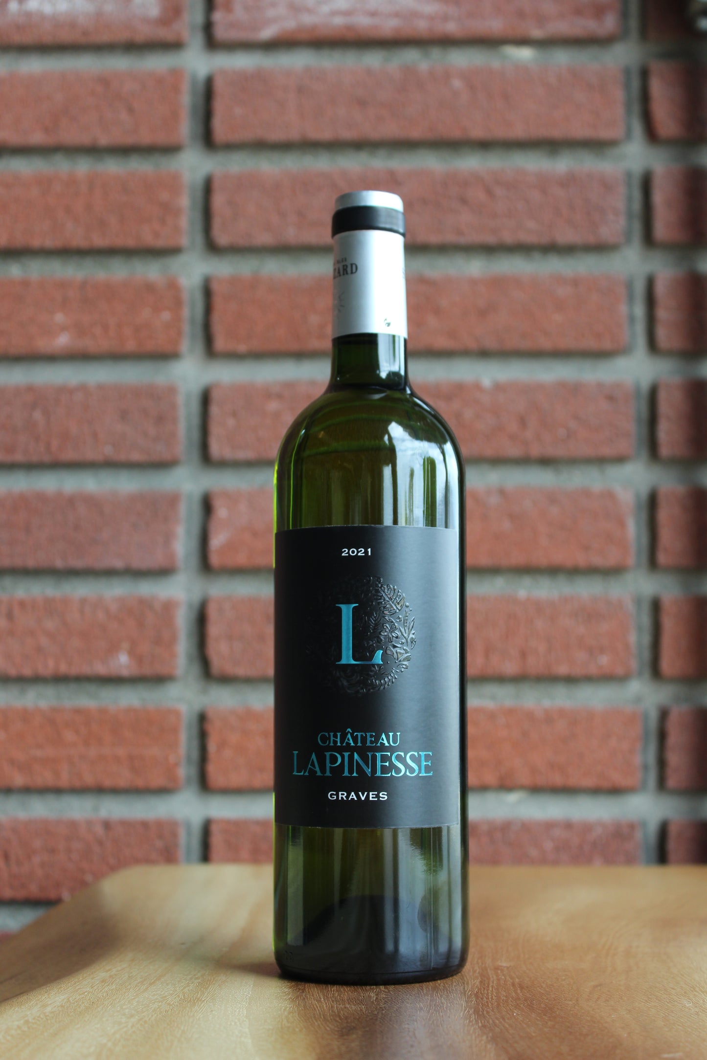 bottle of chateau lapinesse graves bordeaux blanc - semillon, with a brick background