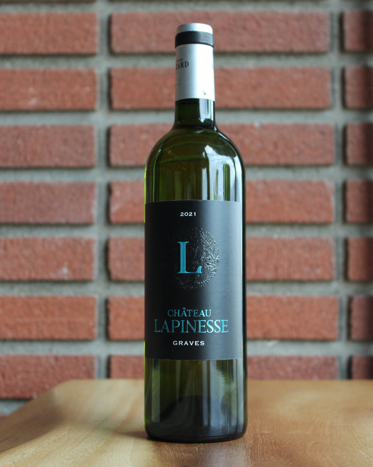 bottle of chateau lapinesse graves bordeaux blanc - semillon, with a brick background
