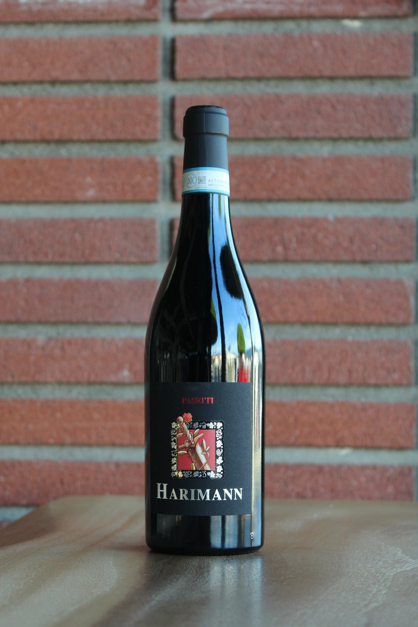 Bottle of Passetti Harimann Montepulciano d'Abruzzo 2018 wine on a wood surface with a red brick background