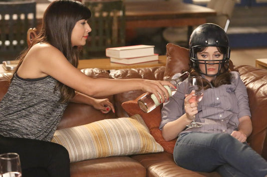 Jess from New Girl getting poured wine while wearing a football helmet