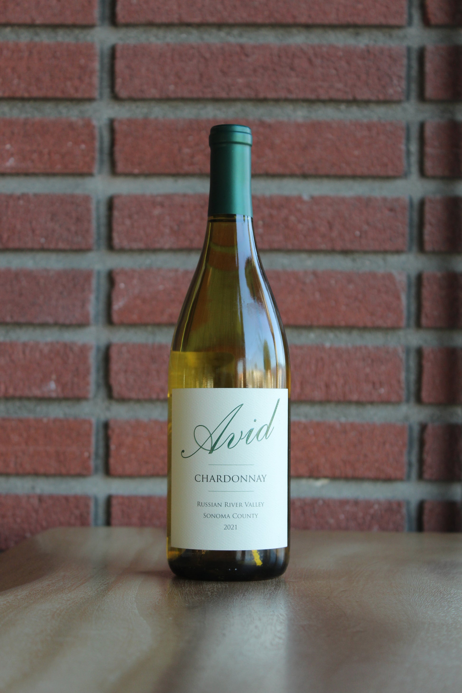Bottle of Avid Russian River Chardonnay wine with a red brick background