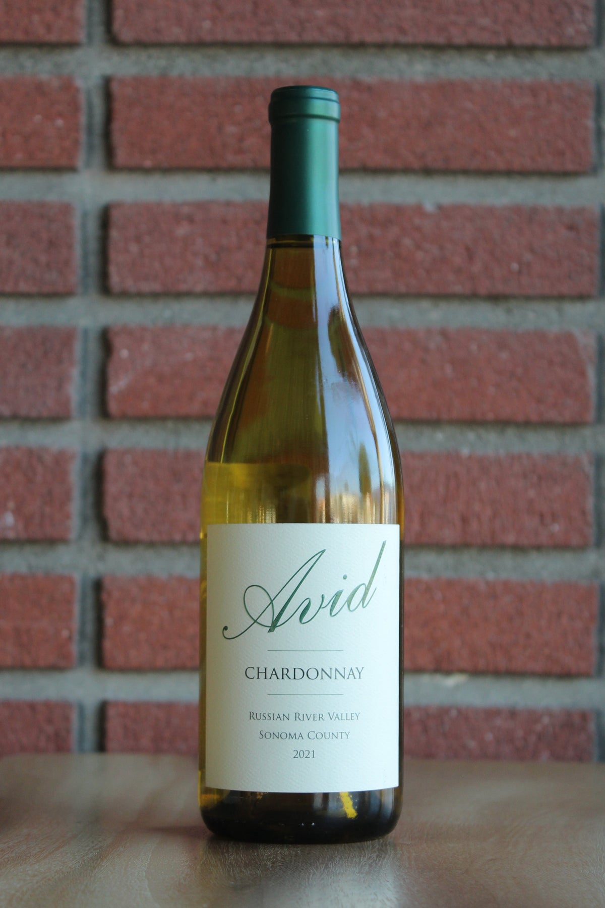 Bottle of Avid Russian River Chardonnay wine with a red brick background