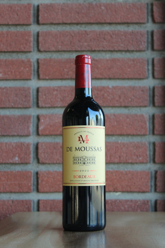 Bottle of Chateau Lynch Moussas "LM Moussas" Bordeaux Rouge 2022 wine with a red brick background