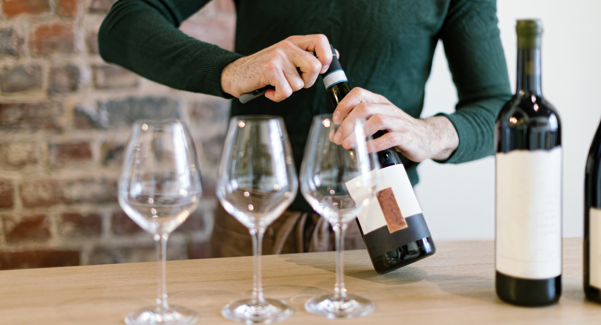 opening of wine bottles behind a table with wine bottles and wine glasses set upon it