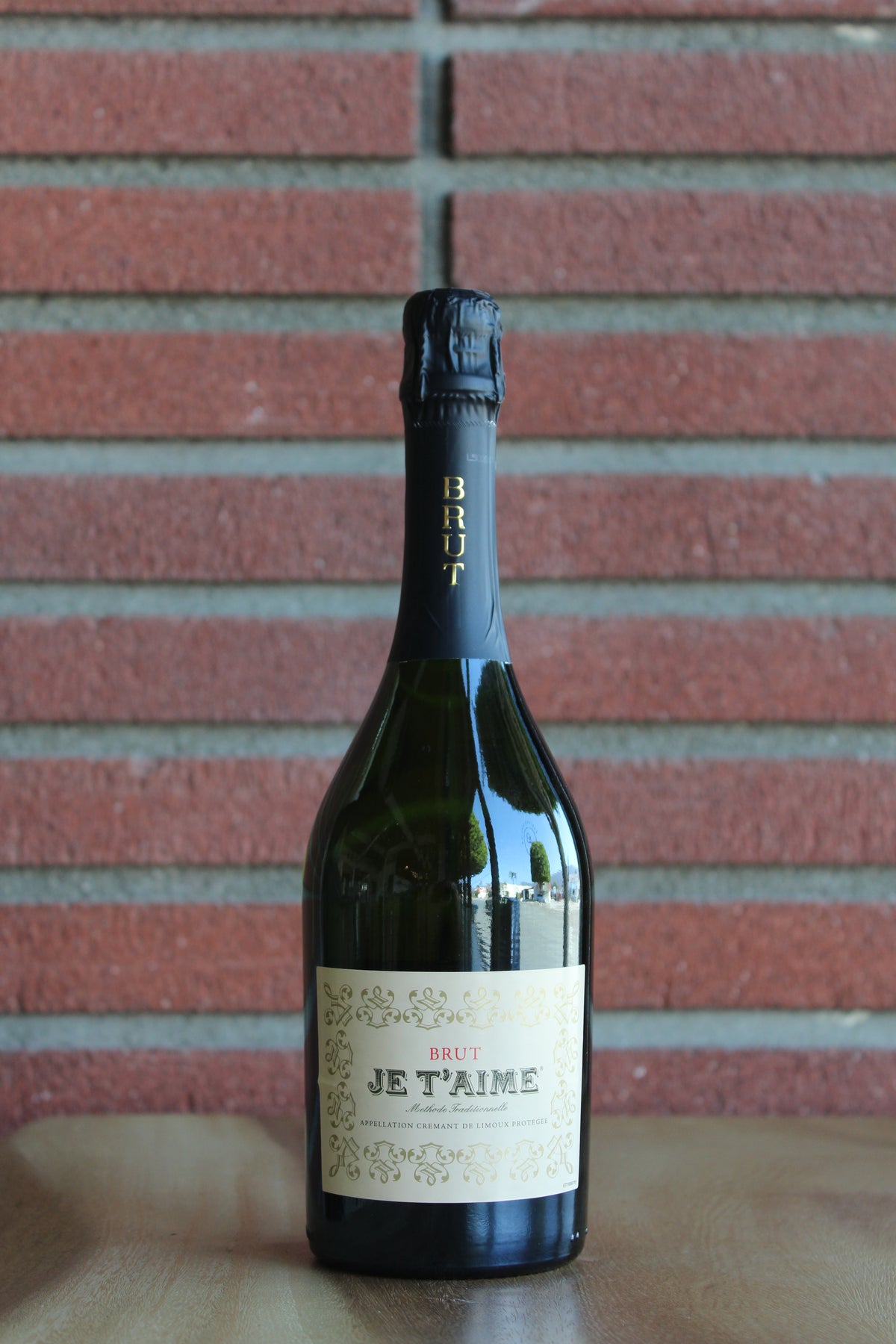 Bottle of Je T'Aime Cremant de Limoux on a red brick background
