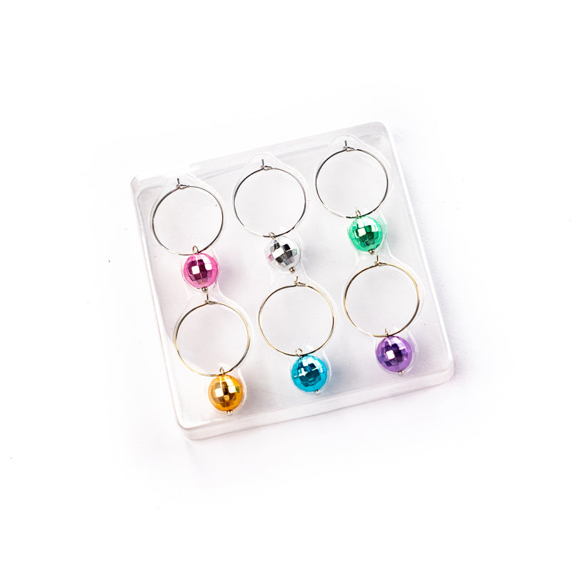 six discoball drink charms of various colors in clear packaging on a white surface