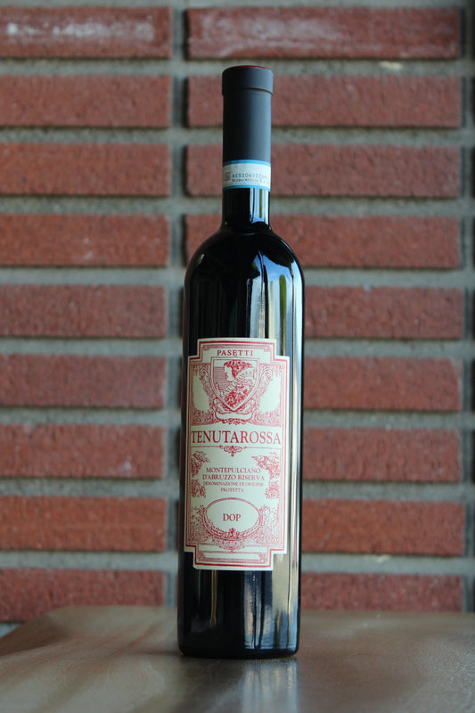 Bottle of Passetti Tenutarossa Montepulciano d'Abruzzo Riserva 2021 wine on a wood surface with a brick background