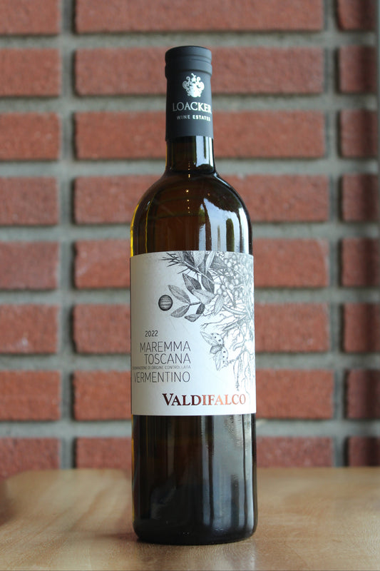 Wine bottle  of Tenute Loacker Valdifalco Vermentino on a wood surface with a red brick background