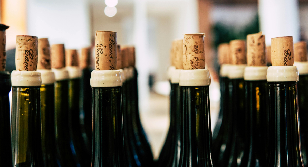 Row of wine bottles with corks in a blurred indoor setting