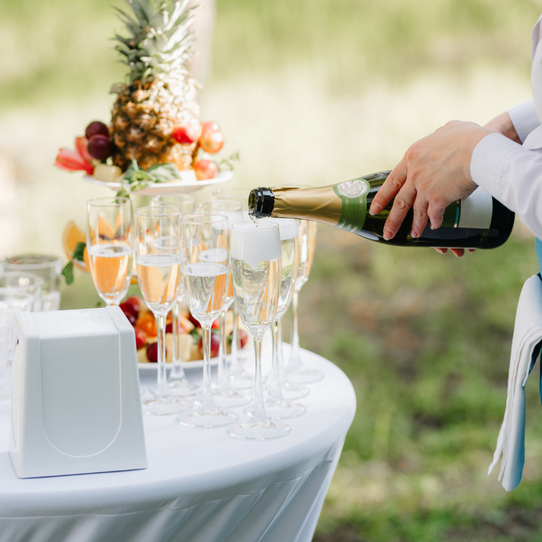 champagne being poured into flutes on a white table with fruit in the background