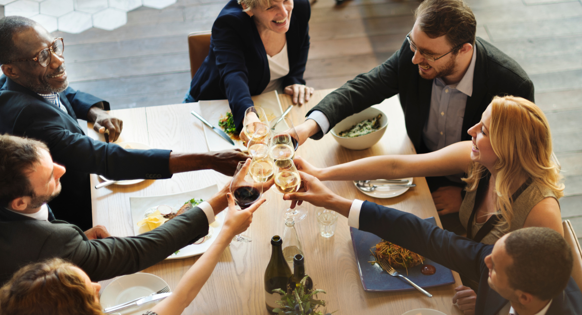 Group of professional toasting at a dinner table with wine glasses.  Image courtesy of Freepik